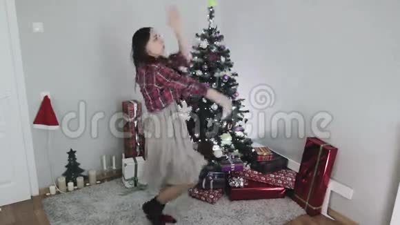 穿灰色连衣裙的年轻女孩正在圣诞树附近跳舞视频的预览图