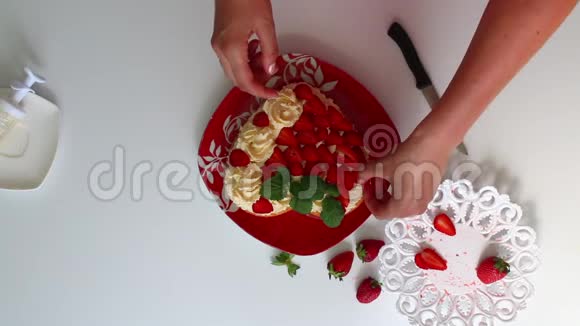 女人用草莓和柠檬香膏装饰饼干碟子旁边是一个切片草莓视频的预览图
