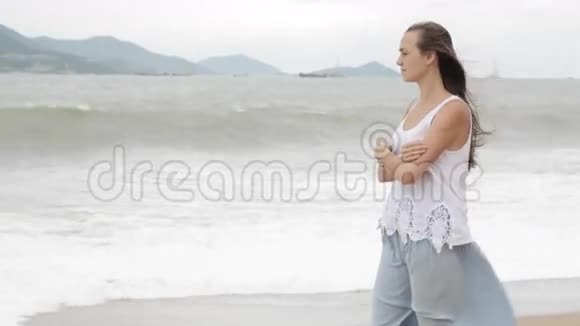 年轻女子站在海滩上天气不好看着大海视频的预览图
