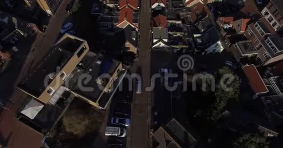 房屋屋顶上方的空中镜头在荷兰无人机飞过城市的屋顶和道路视频的预览图