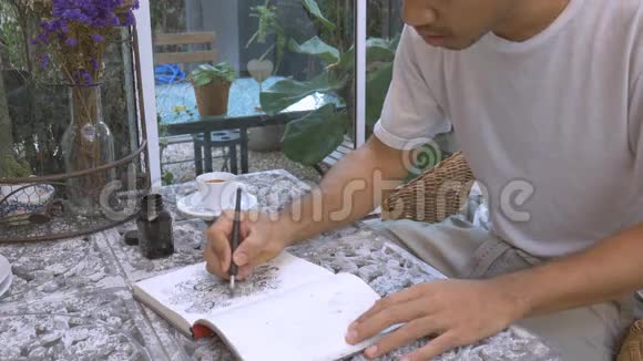 亚洲男人用黑色墨水在纸上画涂鸦线视频的预览图