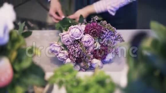 靠近一个女人花店做一束紫色的花倾斜起来视频的预览图