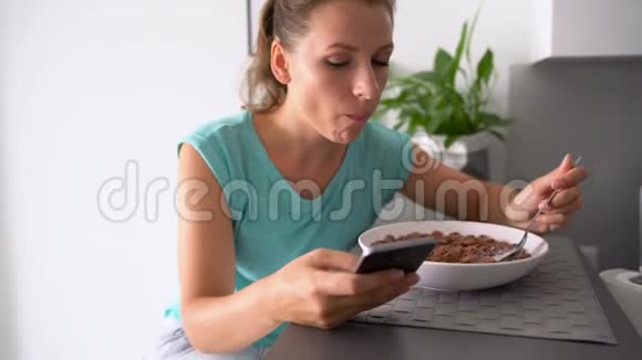 女人吃早餐时用智能手机视频的预览图