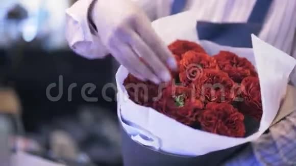 在花店工作的女人正在调整一束红玫瑰花束视频的预览图