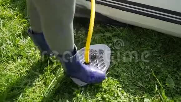 穿胶靴的女人在绿草上用水泵充气漂流艇高清慢镜头视频的预览图
