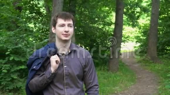 阳光明媚的一天一个年轻的商人穿过树林视频的预览图