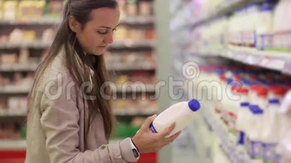 一位年轻的女士在超市的一个奶制品区选择了一瓶牛奶视频的预览图