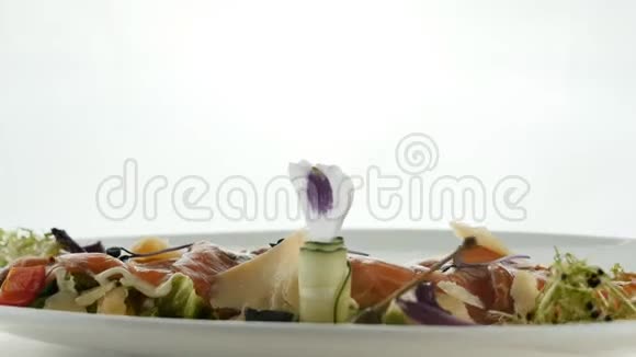 美味的红鱼或三文鱼卷与果冻橙鱼子酱和绿色沙拉混合在盘子上模糊的彩色背景视频的预览图