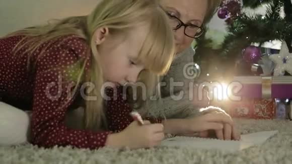 祖母和孙女躺在圣诞树附近的地板上视频的预览图