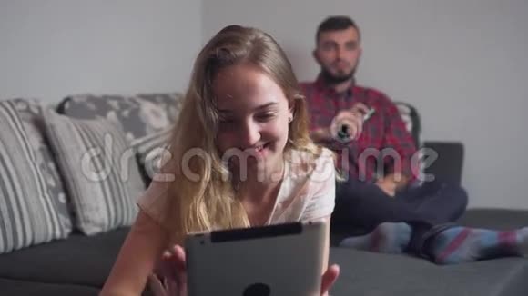 年轻夫妇晚上用电视和平板电脑消费视频的预览图