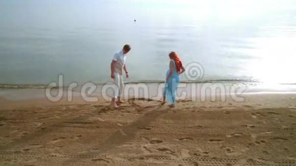 浪漫的情侣在沙滩上吸引着心稳定的情侣镜头视频的预览图