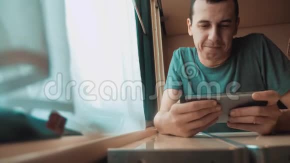 男人在智能手机上玩网络游戏强烈的情绪愤怒的男人坐在窗边的火车上缓慢的生活方式视频的预览图