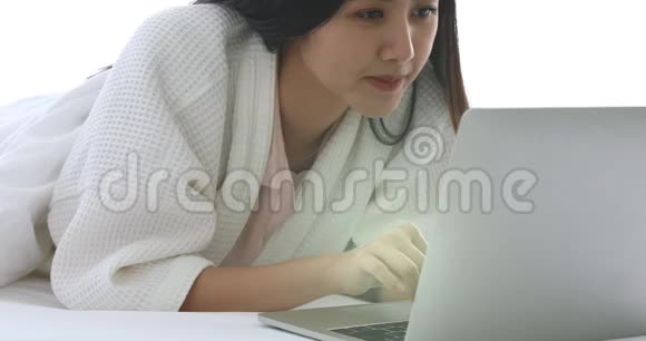 漂亮的亚洲女人在床上用笔记本视频的预览图