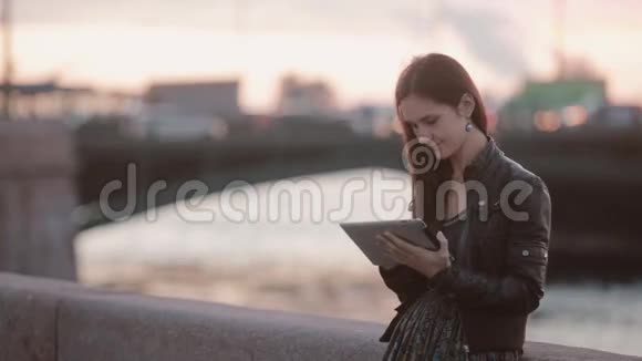 漂亮的年轻女人用平板电脑站在码头的漂亮女士背景模糊的汽车现代技术视频的预览图