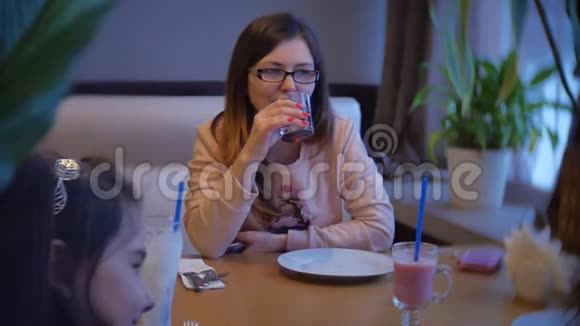 那个女人坐在咖啡馆里喝着一杯玻璃杯女人正在咖啡馆里吃一段慢动作的室内录像视频的预览图