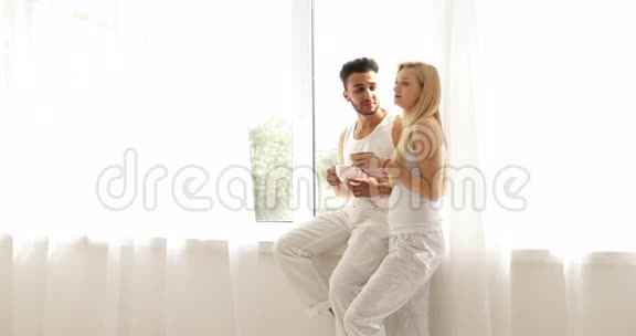 两个人喝咖啡早上坐在窗前混种男人女人微笑视频的预览图