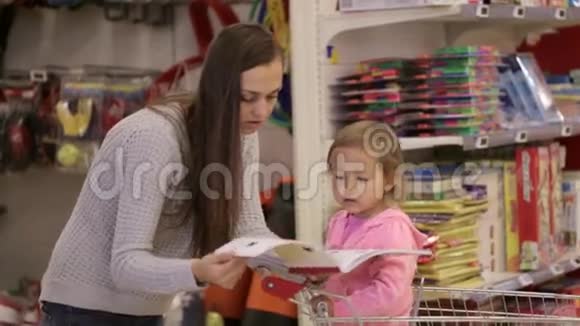小妈妈和小女儿在购物车里挑选超市里的书视频的预览图