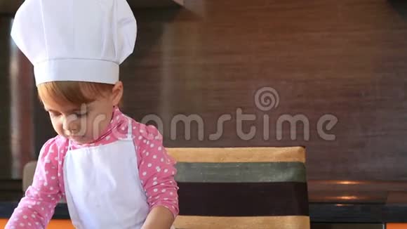 穿着厨师服的小可爱女孩在厨房里玩盘子视频的预览图