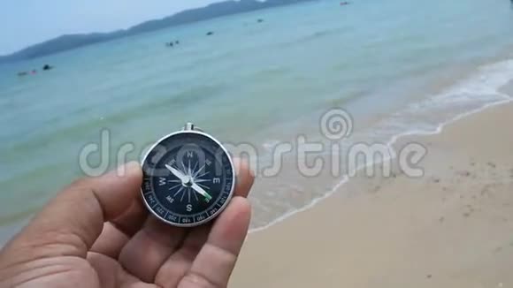 近射手曼德手持罗盘在沙滩上与自然海洋和风环境的声音视频的预览图