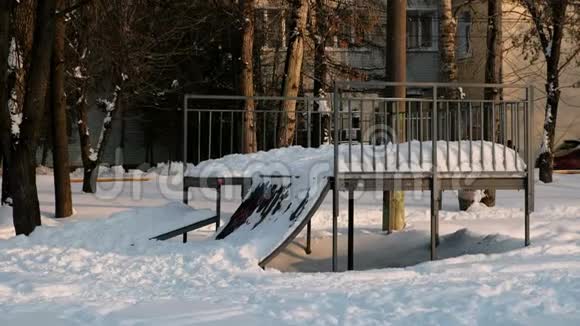 雪天晴冬季城市公园里的滑板车登机公园雪在山上漂移到滑板上视频的预览图