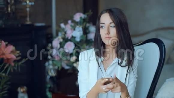 一个女人用智能手机发短信坐在室内客厅的椅子上视频的预览图
