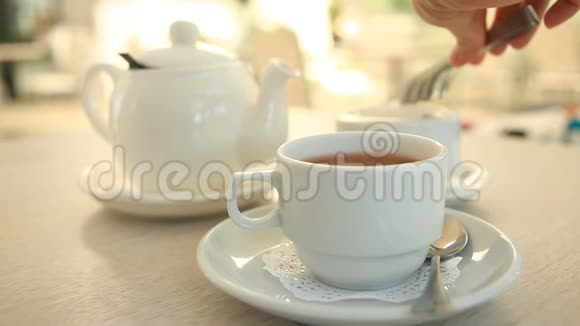 有人从一个糖碗里拿出一个用钳子精制的糖放在一个带茶的沙库里视频的预览图