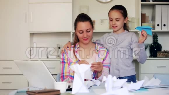 年轻母亲和微笑女儿学习做纸雕像的肖像视频的预览图
