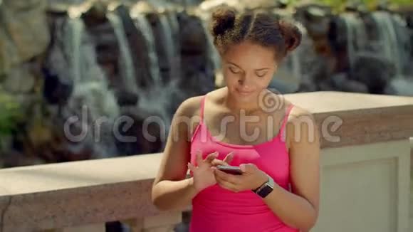 女孩在智能手机上看照片在公园打电话的拉丁女孩视频的预览图