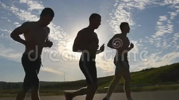日落时分强壮的男人在乡间小路上慢跑的剪影马拉松跑男子慢跑训练组视频的预览图