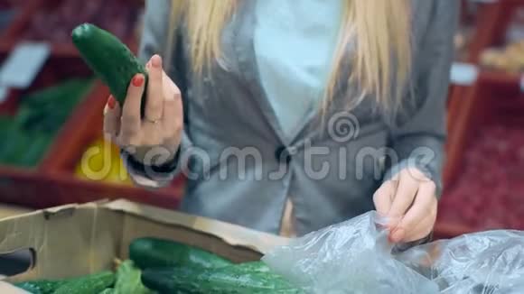 在超市的杂货店把黄瓜放进塑料袋视频的预览图