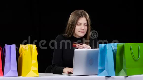 女孩用她的信用卡和笔记本电脑在线购物黑色视频的预览图