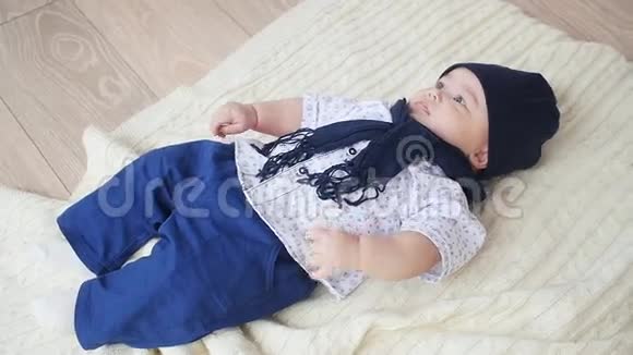 漂亮的小男孩躺在白色的地毯上视频的预览图