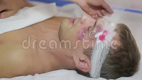 护士包扎头部绷带一个受伤的男人脸上有瘀伤视频的预览图