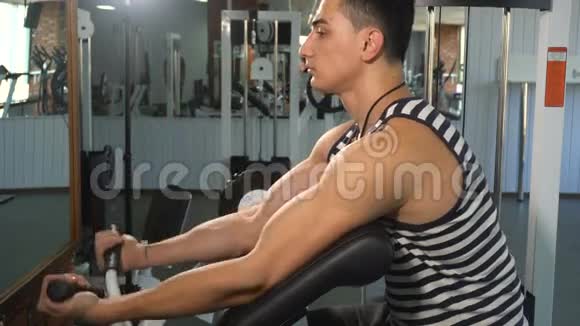强壮的男人在肱二头肌机上做运动视频的预览图