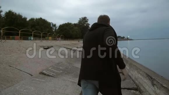 穿着长毛衣的人沿着海滩跑水树月亮在背景慢莫后景稳定镜头视频的预览图