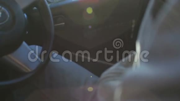 男司机在阳光下坐在车里太阳光束方向盘视频的预览图