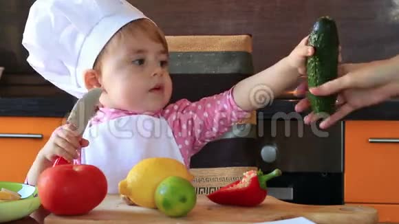 可爱的小宝宝装扮成厨师这幅可爱的肖像画帮助妈妈准备沙拉视频的预览图
