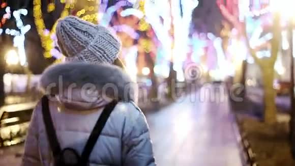 一位年轻的亚洲女孩沿着一个街道公园散步那里有树木用彩色花环照亮视频的预览图