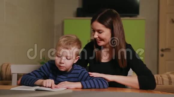 母子俩坐在自家的厨房里学着看书视频的预览图