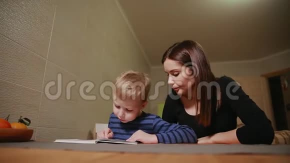 母子俩坐在自家的厨房里学着看书视频的预览图