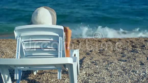 坐在沙滩上晒太阳的年轻女子视频的预览图