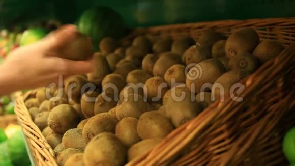 一个女人在蔬菜货架上的超市里买蔬菜和水果猕猴桃视频的预览图
