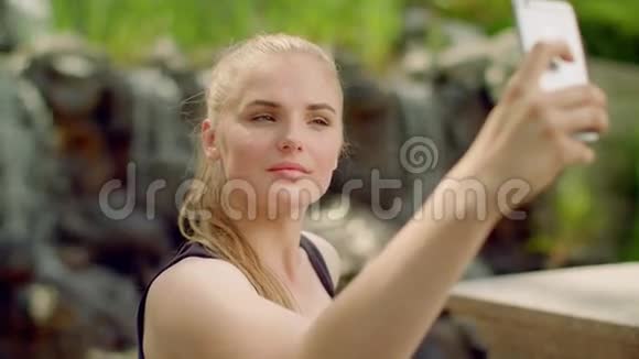 金发女人在公园自拍时尚女孩在电话里自拍视频的预览图