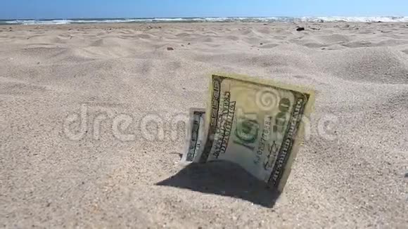 钱一半被沙子覆盖在海滩特写上视频的预览图