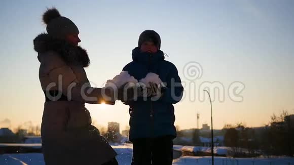 女孩和孩子把雪洒在自己身上在日落的冬季公园里尽情享受视频的预览图