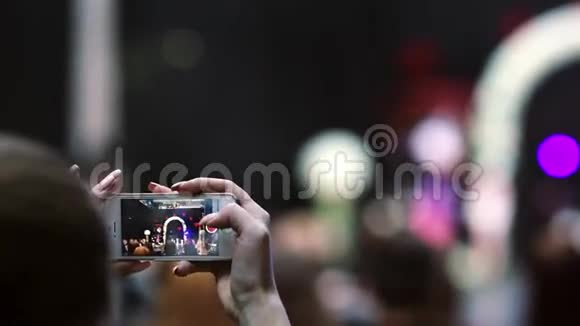 特写双手握着智能手机拍着时装秀的视频在智能手机屏幕上可以看到模型视频的预览图