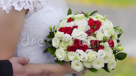 新娘手里拿着一束红白玫瑰花一个穿着白色裙子的女孩站在那里穿着五颜六色的花视频的预览图