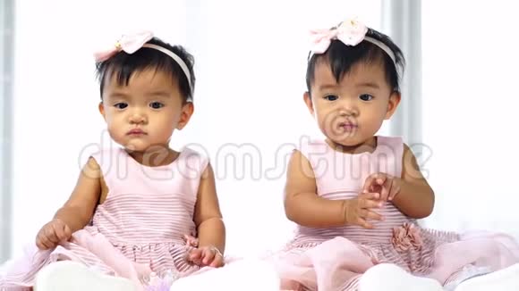 两个穿粉色连衣裙的双胞胎婴儿视频的预览图