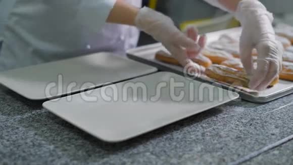 糖果店里的糖果店戴手套的女人用盘子上的一张烤盘来转移蛋糕装饰着的小屋视频的预览图