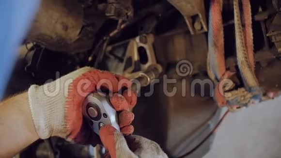 机械师用悬挂在修理车间的汽车马达外壳上的工具紧固螺栓视频的预览图
